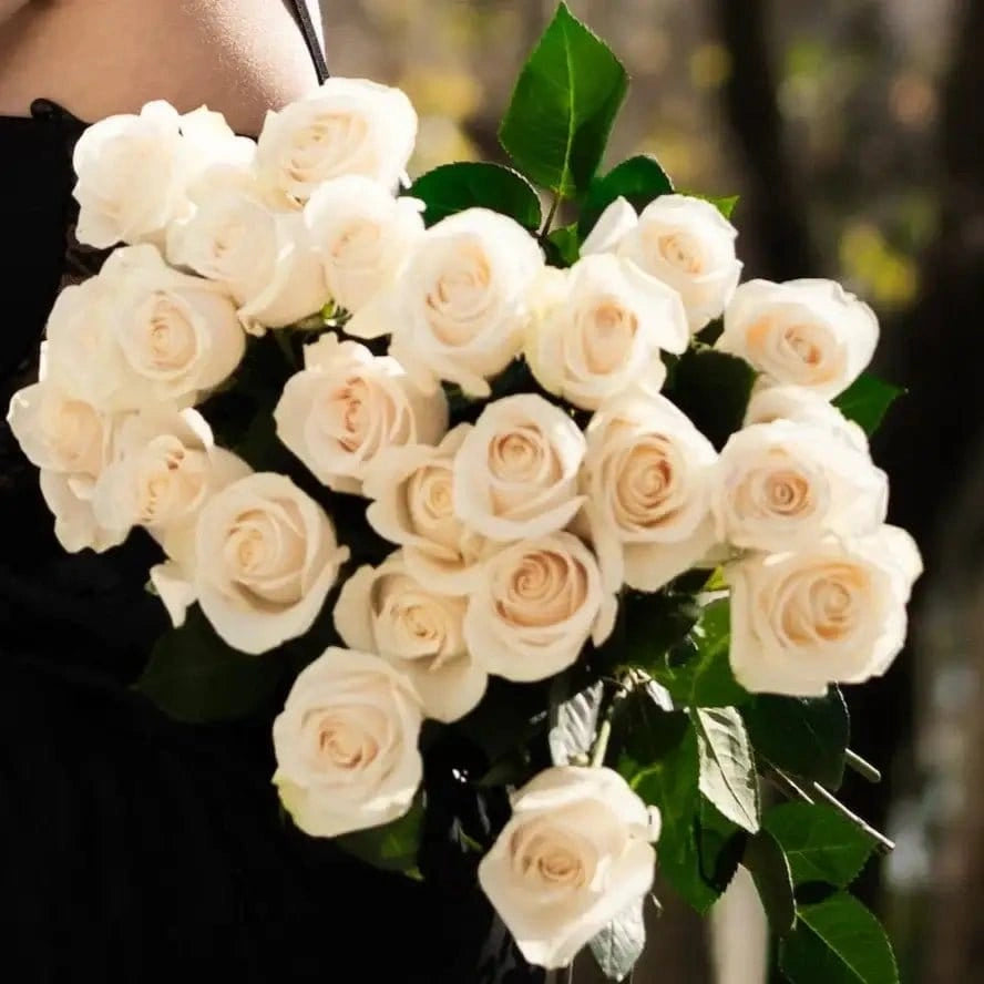 Bouquet de rosas brancas premium QRoses com folhas verdes naturais e acabamento elegante em ambiente exterior sofisticado.
