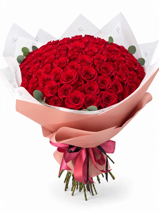 Bouquet da QRoses com 100 rosas vermelhas, envolvido em papel rosa e branco com fita da marca.
