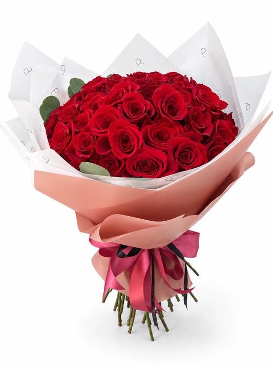 Bouquet da QRoses com 50 rosas vermelhas, envolvido em papel rosa e branco com fita da marca.