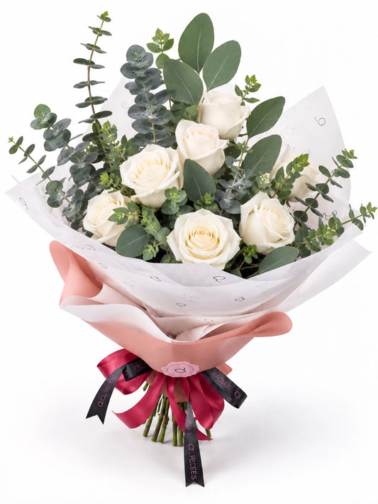 Bouquet Essential da QRoses com rosas brancas e eucalipto, envolvido em papel rosa e branco com fita da marca.