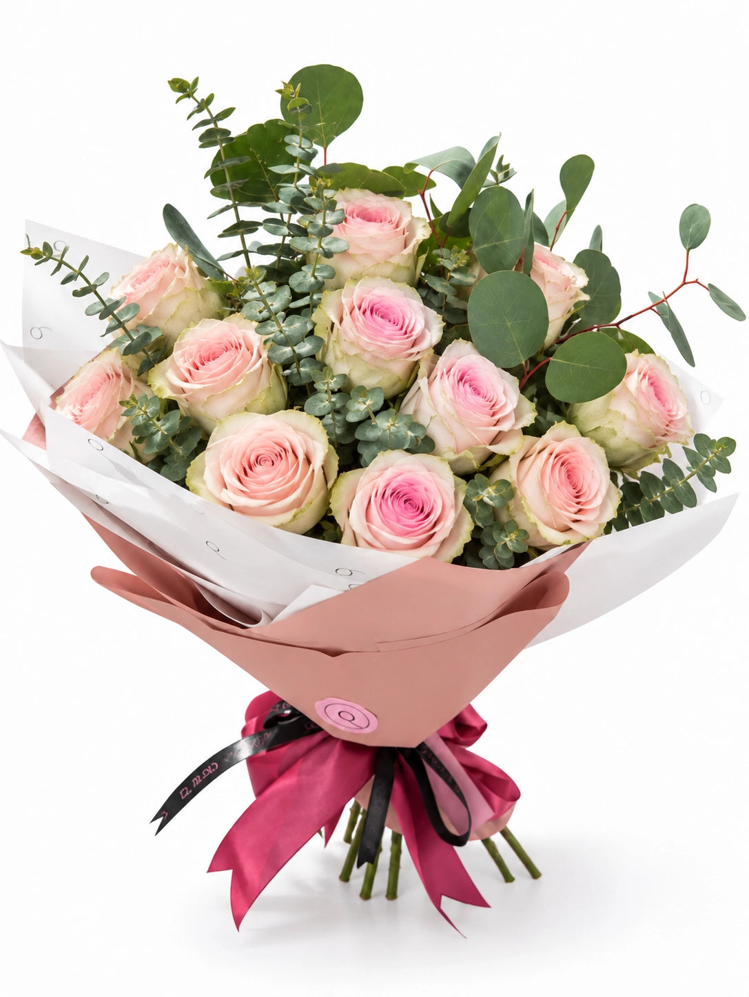 Bouquet Premium da QRoses com 12 rosas rosa suave e eucalipto, envolvido em papel rosa e branco com fita da marca.