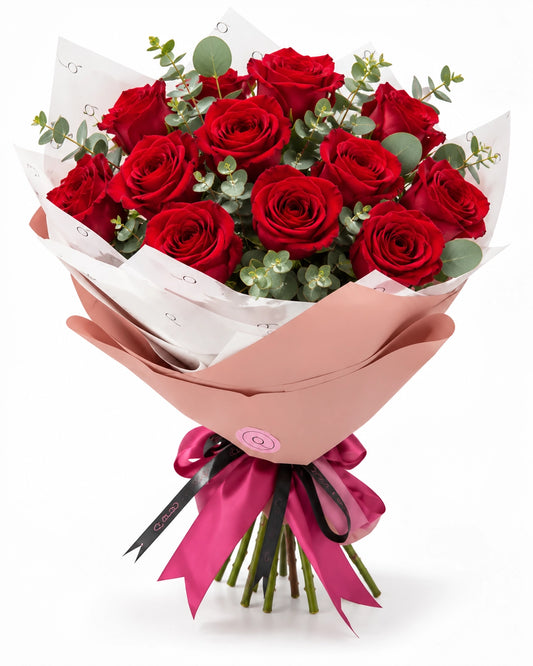 Bouquet premium QRoses com 12 rosas vermelhas naturais, eucalipto, embrulho rosa elegante e laço fúcsia