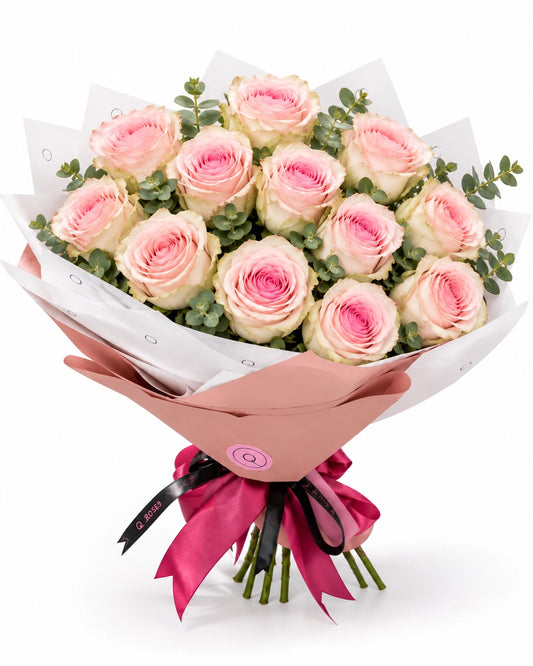 Bouquet premium QRoses com 13 rosas Frutetto rosa e eucalipto, envolvido em papel rosa empolvado e branco, com laço fúcsia.