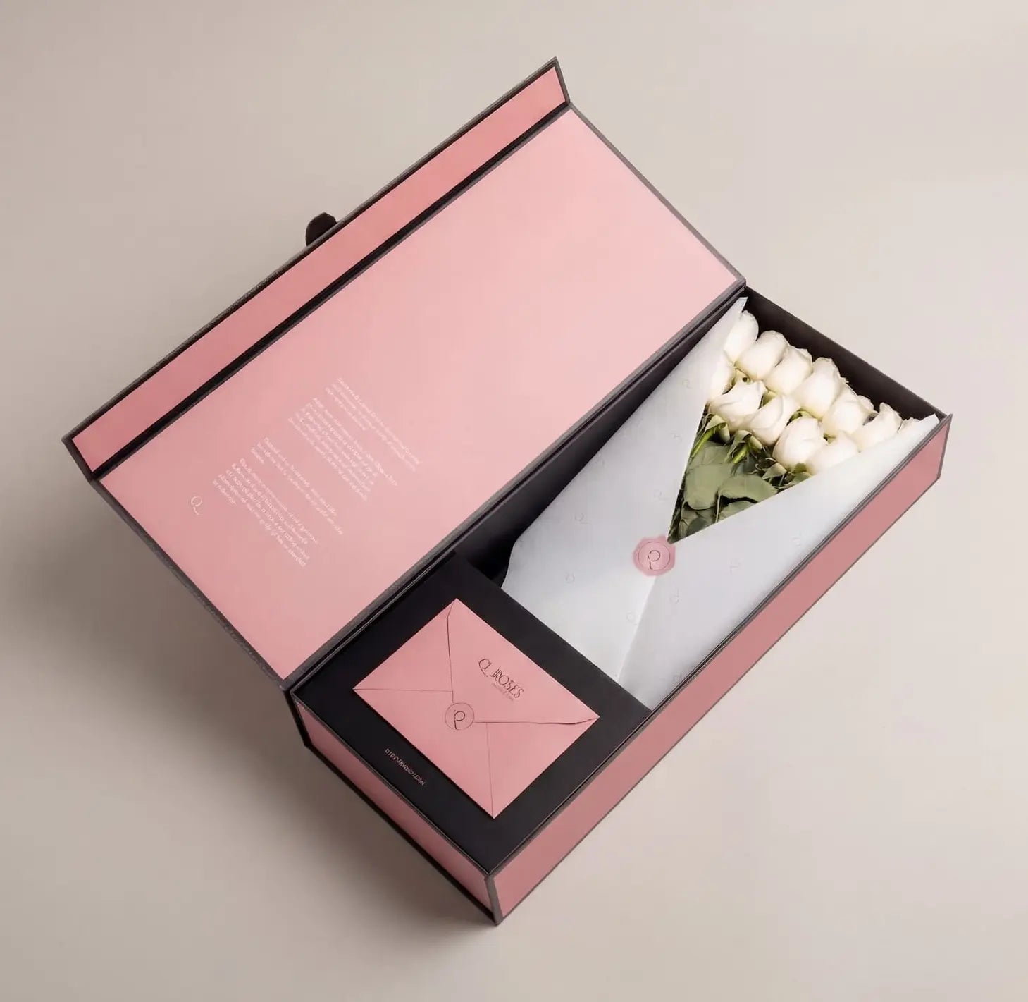 Caixa QRoses aberta com rosas brancas premium embrulhadas em papel elegante e cartão personalizado no interior.