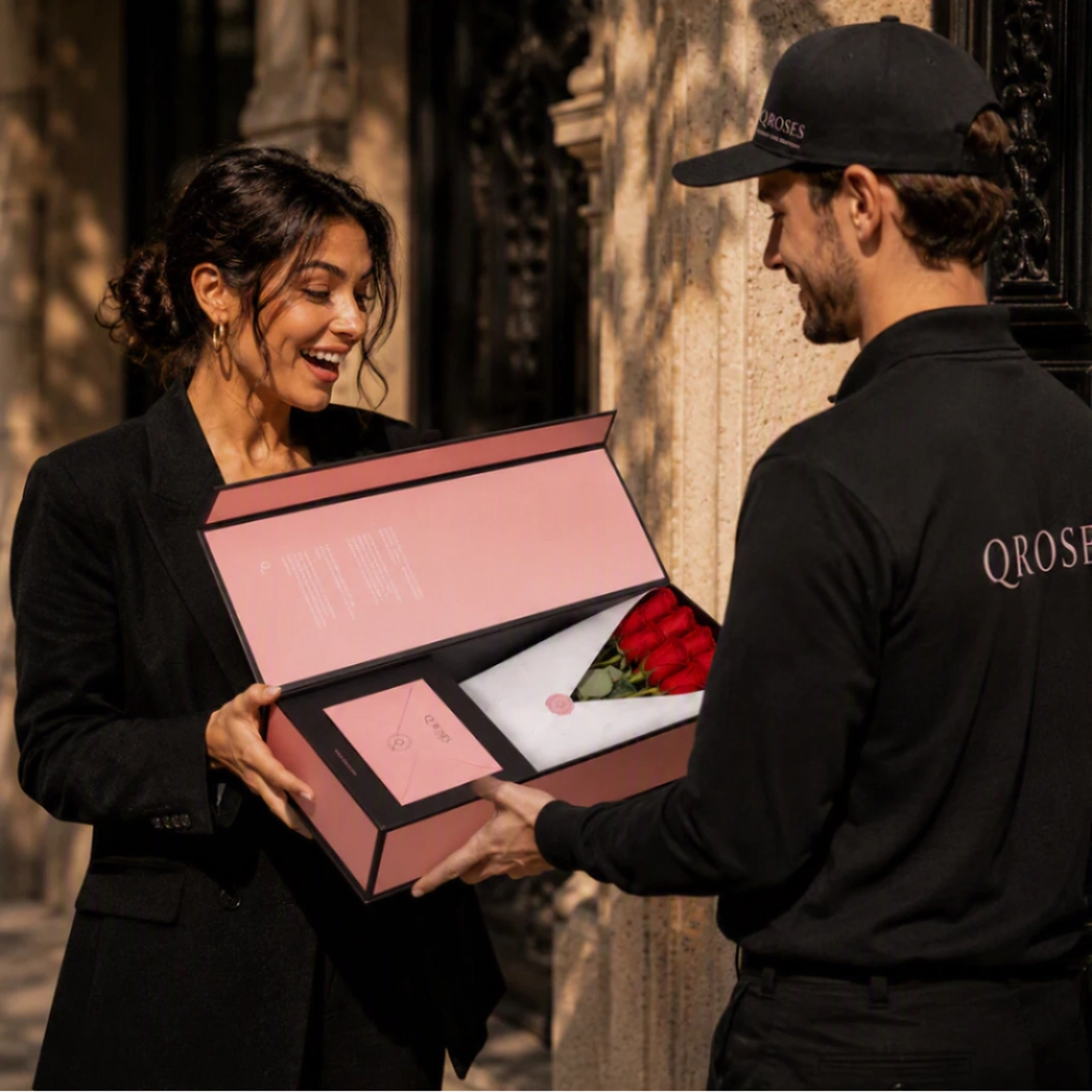 QRoses delivery specialist presenting a luxury rose arrangement in an elegant Signature Box to a smiling customer at her doorstep, showcasing premium flower delivery service in Portugal.