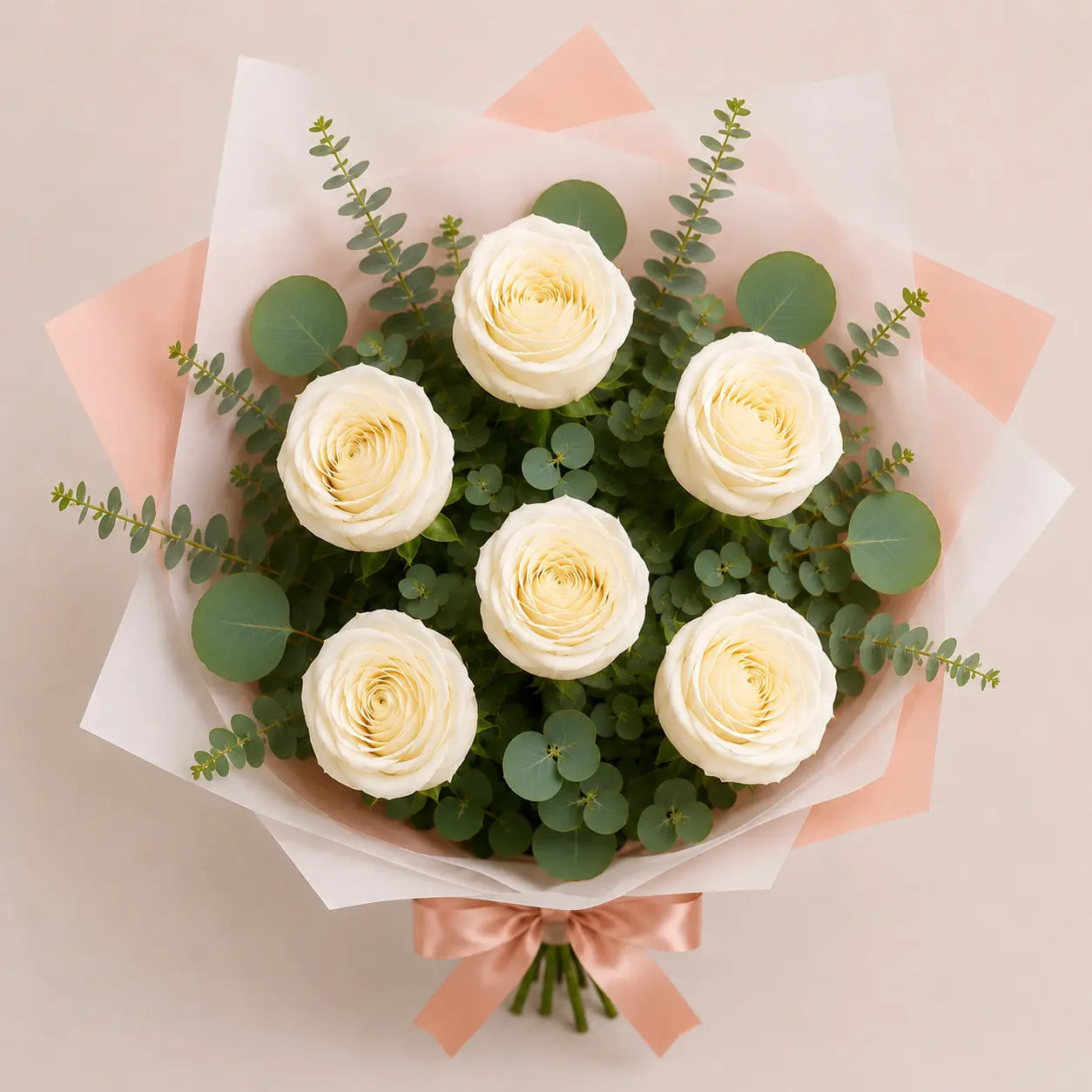 Vista superior do Ramo Essencial de 5 ou 6 rosas brancas, envolvidas em papel artístico branco e rosa, com eucalipto e laço acetinado rosa sobre fundo neutro.