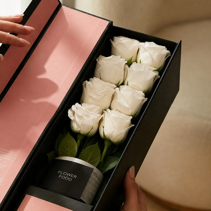 Close-up of the QROSES FLUTE gift box with eight premium white roses, premium flower food container, and elegant blush pink interior packaging.