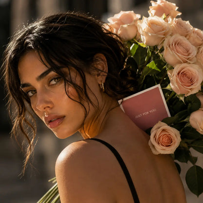 Mulher elegante com bouquet de rosas cor-de-rosa premium QRoses e cartão, num retrato sofisticado com luz natural e estilo editorial de luxo.