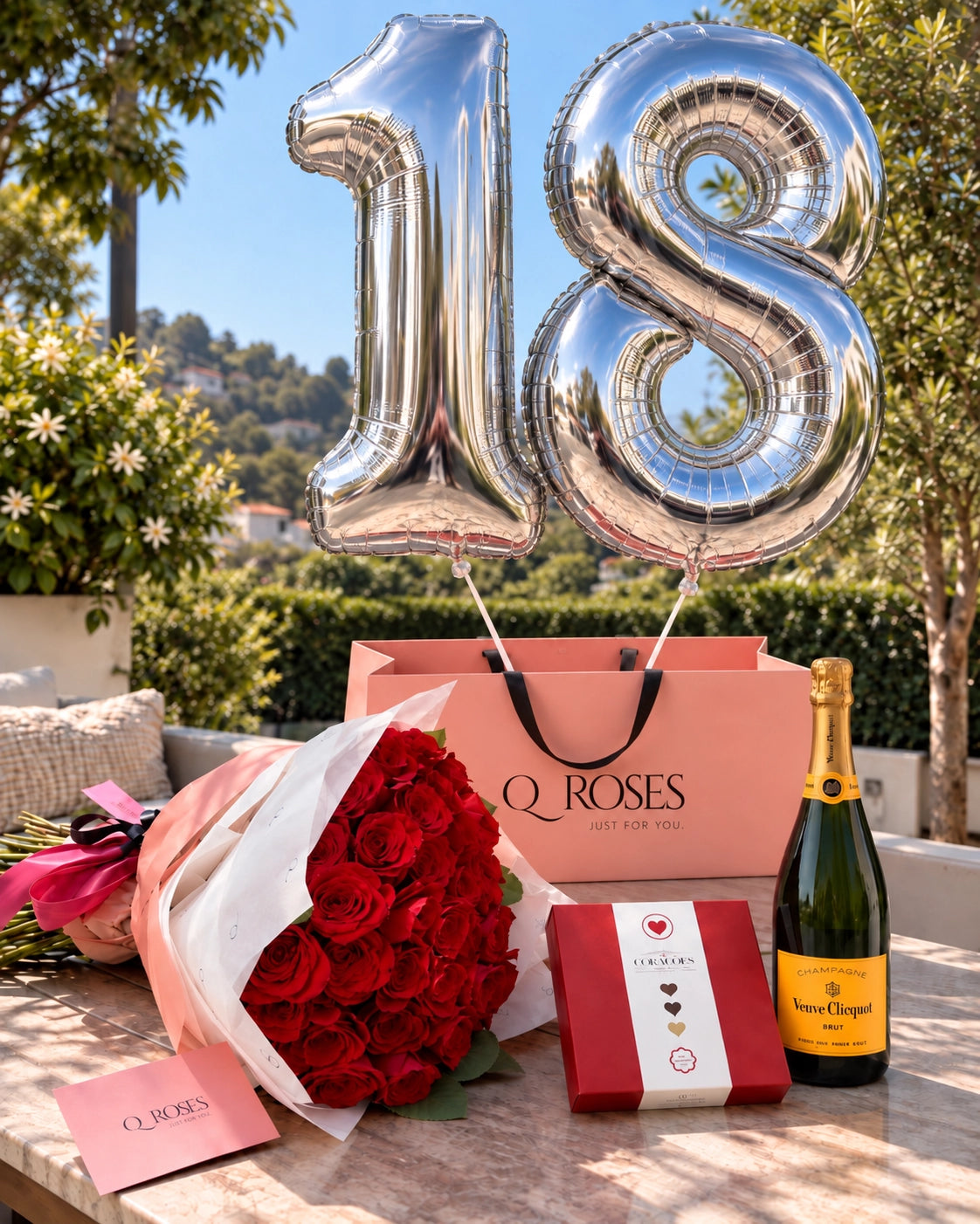 QRoses 18th celebration gift set with 50 red roses, silver 18 balloons, Arcádia chocolates and Veuve Clicquot champagne.