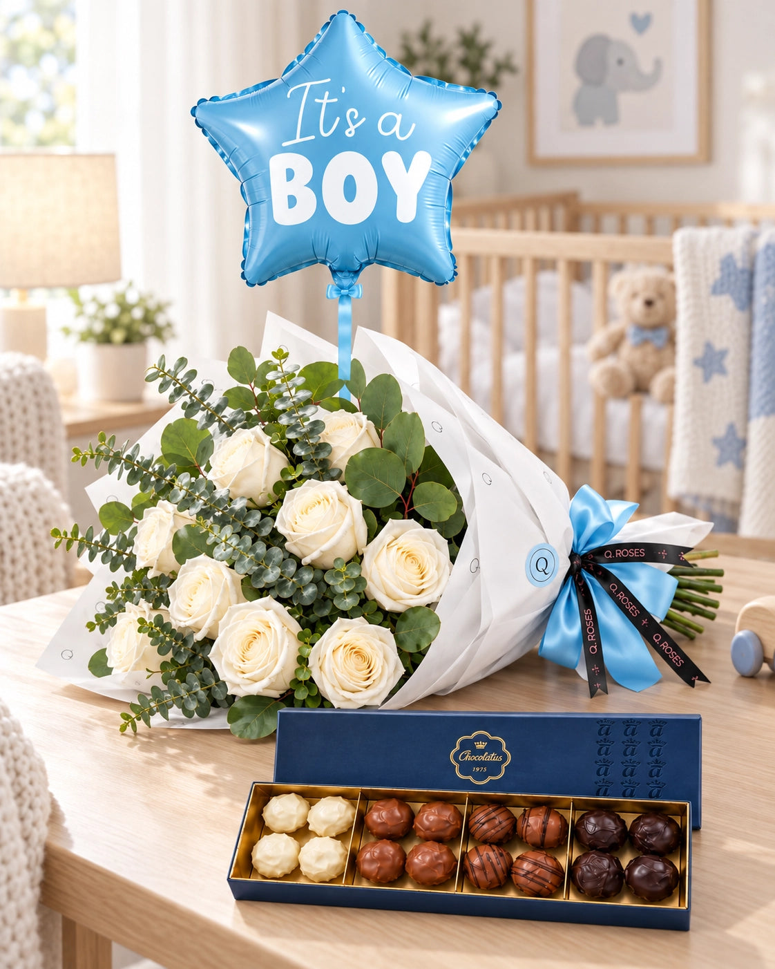 Bouquet de rosas brancas QRoses com balão azul It's a Boy e chocolates Arcádia num quarto de bebé com berço e decoração em azul e creme.