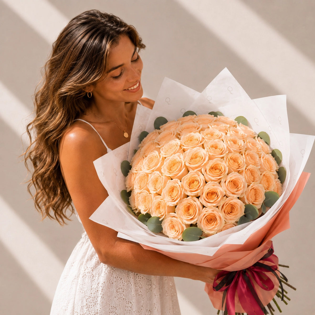 Mulher a segurar um buquê de alta gama de 50 rosas pêssego QRoses.