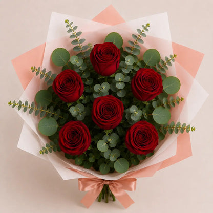 Vista cenital do Ramo Essencial de 5 ou 6 Rosas Vermelhas da QRoses, com papel artístico, eucalipto e laço premium.