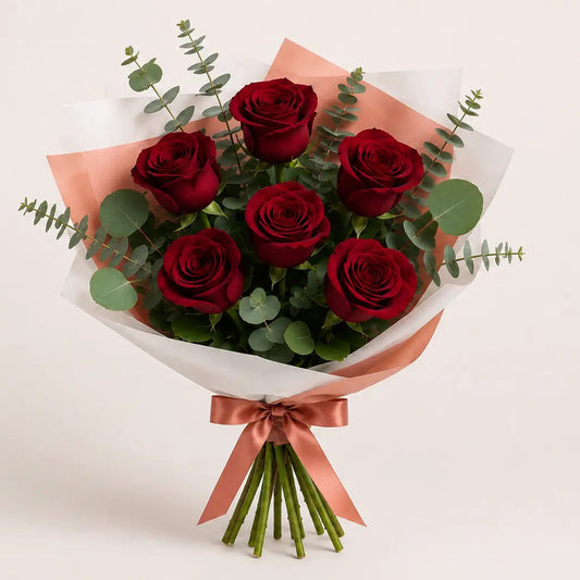 Ramo Essencial de 5 ou 6 Rosas Vermelhas da QRoses, com papel artístico, eucalipto e laço premium.