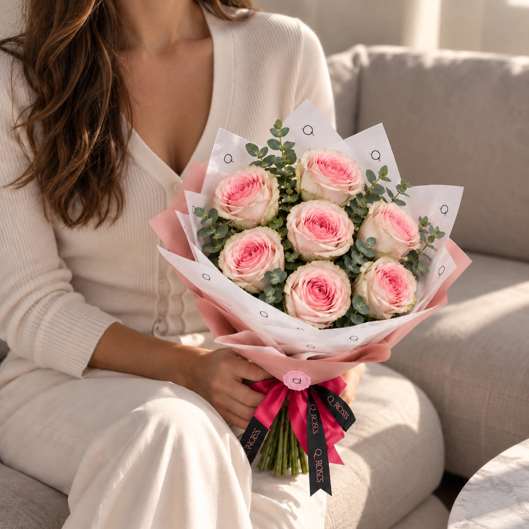 Mulher com Ramo Essential de rosas cor-de-rosa mostrando as dimensões do ramo
