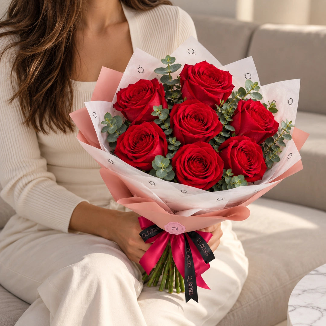 Mulher com Ramo Essential de rosas vermelhas mostrando as dimensões do ramo